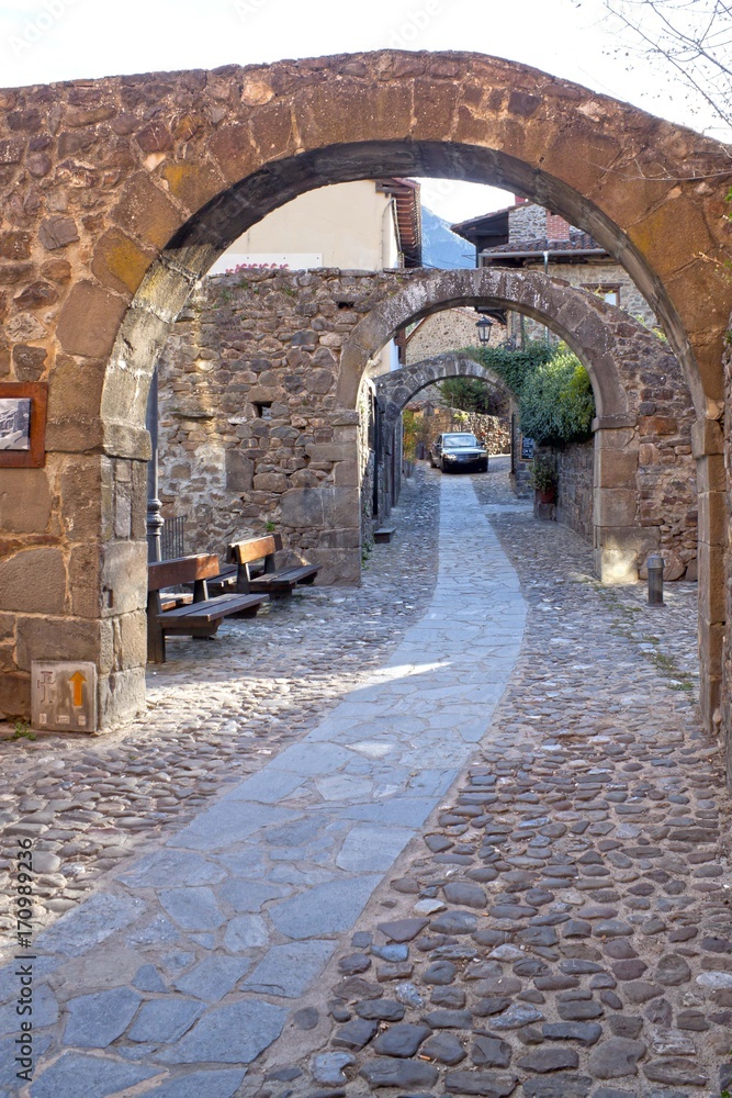 street full of stone archs with a car in Potes, Spain