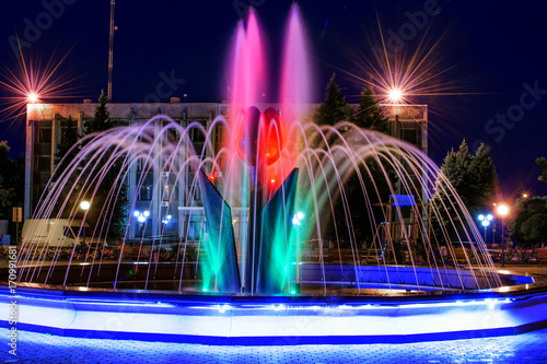 A beautiful illuminated city fountain Flower of a tulip at night. View of the town Pokrov in Ukraine, 2017 photo