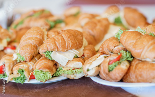 Butter croissants with chicken ham,cheese and parsley on white plate.Croissant sandwich with cheese and vegetables for healthy snack.Appetizer/Fresh Croissants, Breakfast sandwiches.Picnic summer food