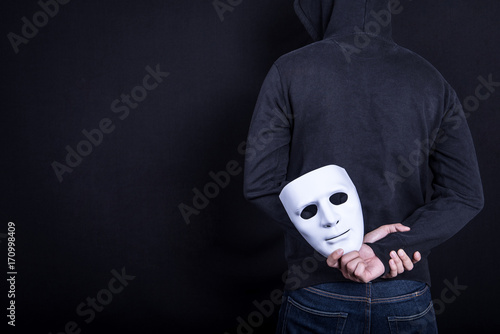 Fotografie Mystery man holding white mask in the back