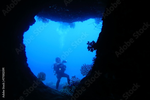 海底の洞窟内で写真撮影するダイバー
