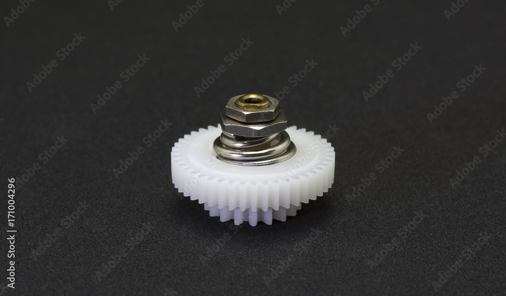 Plastic gear spare part in the fragment of machine on black background. Plastic gear spare part in the fragment of machine on black background.