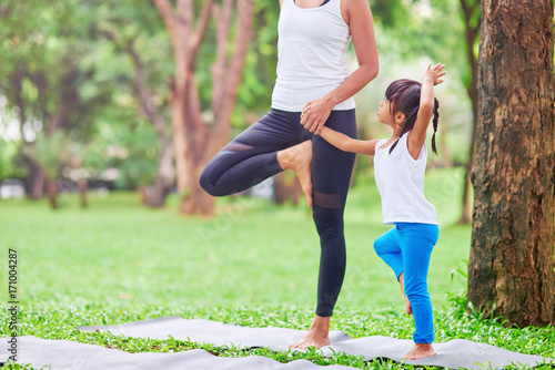 Pleasant caring mother teaching her little daughter to practive yoga