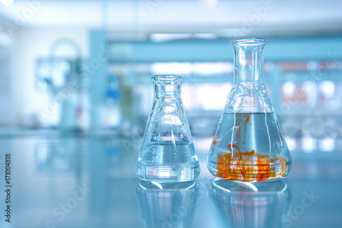 orange fluid in water in flask glassware in science chemical laboratory