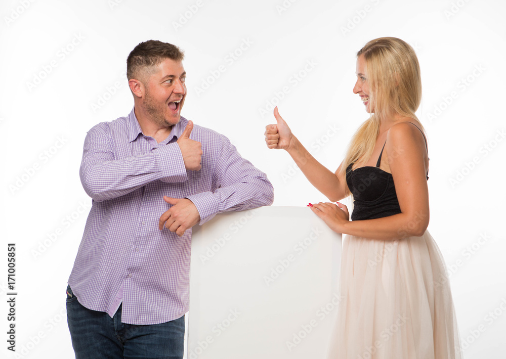 Young playful couple portrait of a confident businessman showing presentation, pointing placard gray background. Ideal for banners, registration forms, presentation, landings, presenting concept. Young playful couple portrait of a confident businessman showing presentation, pointing placard gray background. Ideal for banners, registration forms, presentation, landings, presenting concept.