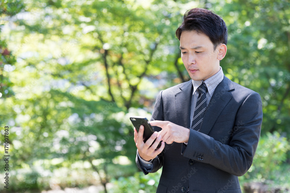 asian businessman using smart phone in park asian businessman using smart phone in park