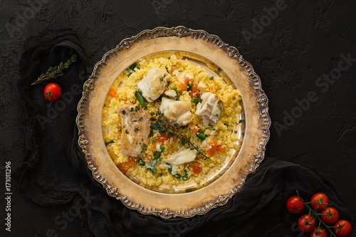 Couscous with fish and vegetables on stone table