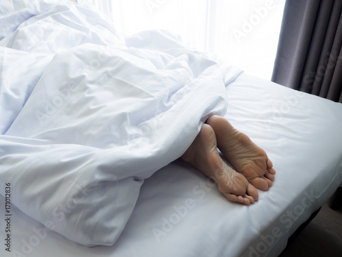 Feet of sleeping woman in white bed room.feet of a young woman lying in bed close up.