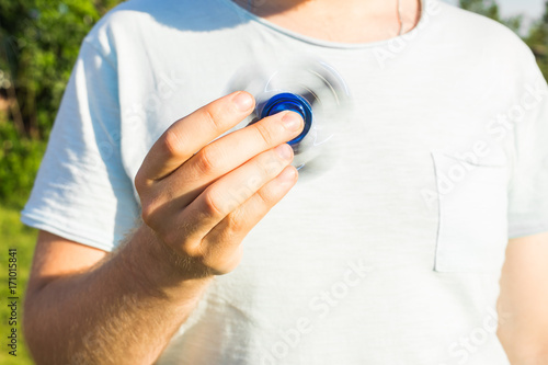 Man playing with a blue spinner fidget toy, close up photo