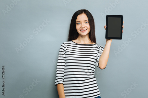 Positive delighted young woman demonstrating her device