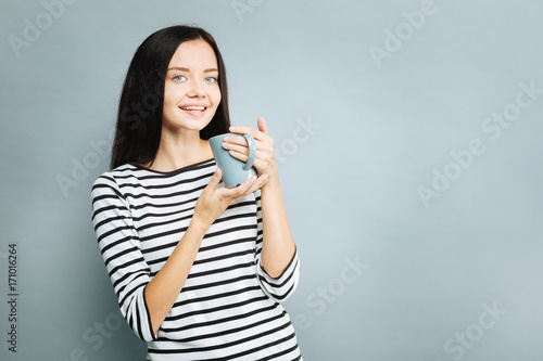 Delighted brunette posing on camera with tea