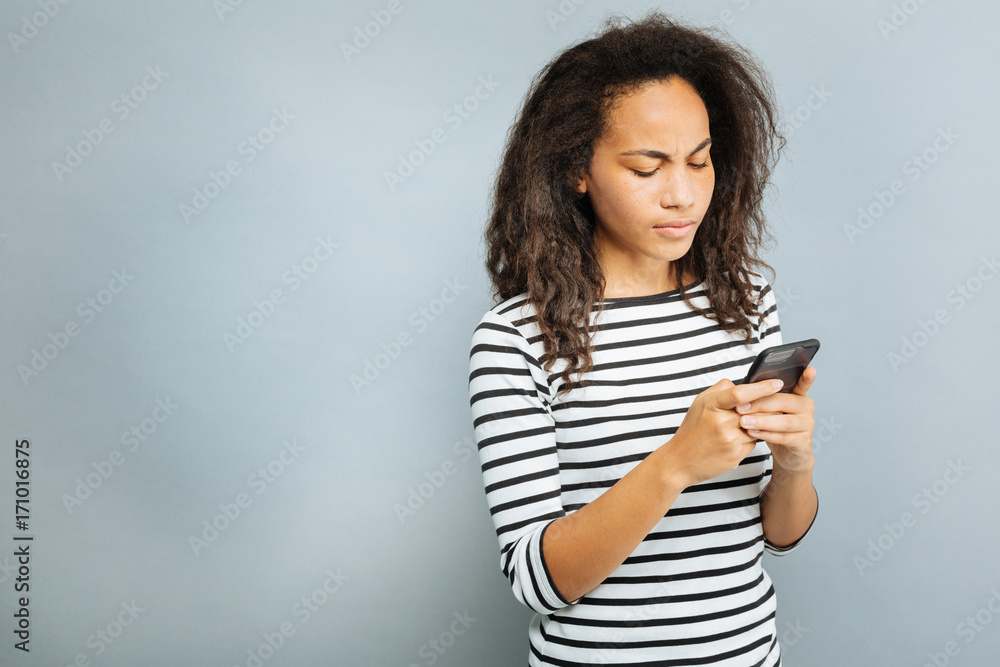 Serious young female looking at screen of her phone Serious young female looking at screen of her phone