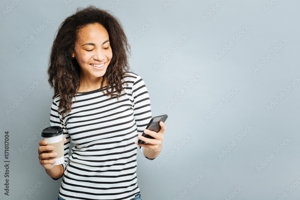 Positive delighted woman looking at her mobile phone Positive delighted woman looking at her mobile phone
