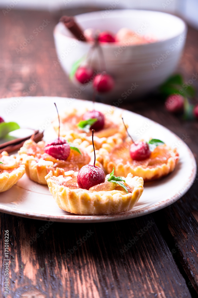 Apple caramel little tarts on white plate and brown rustic background. French tatin with paradise apple. Apple caramel little tarts on white plate and brown rustic background. French tatin with paradise apple.