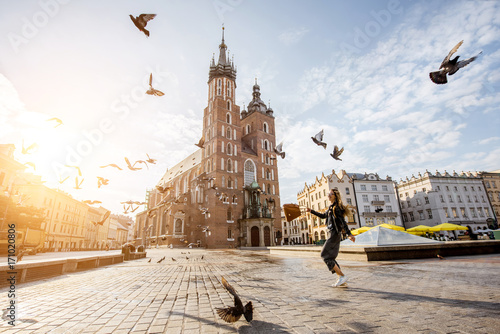 View on the central square and famous st. Marys basilica with pigeons flying during the sunrise in Krakow, Poland