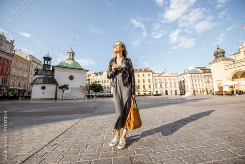 Lifestyle portrait of a stylish woman walking on the Market square during the morning light in Krakow, Poland photo