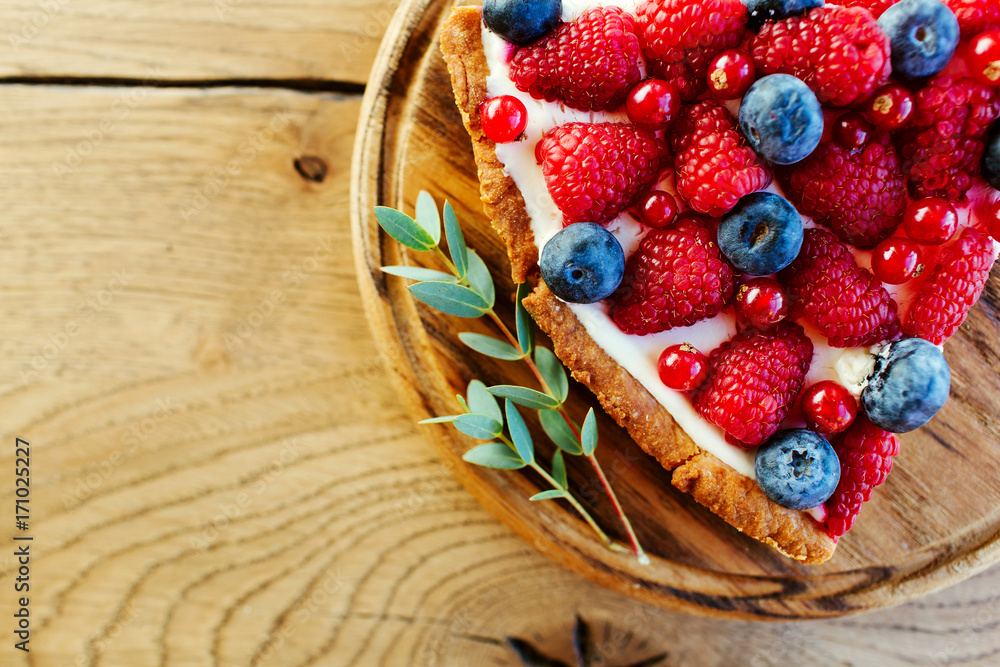 A piece of berry tart with raspberries and blueberries on wooden background with copy space A piece of berry tart with raspberries and blueberries on wooden background with copy space