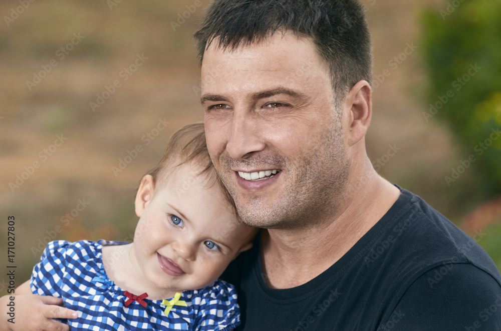 Father is holding his beautiful baby with eyes blue. Father and daughter playing outdoors. Smiling Father is holding his beautiful baby with eyes blue. Father and daughter playing outdoors. Smiling
