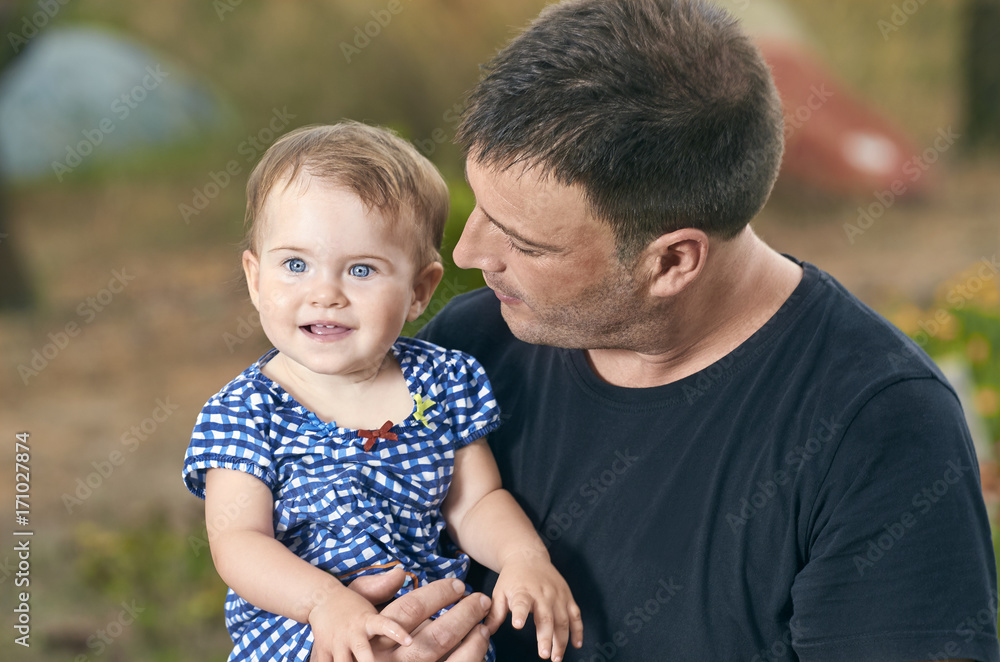 Fototapeta premium Father is holding his beautiful baby with eyes blue. Father and daughter playing outdoors