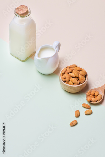 Almonds and milk bottle on light background. Almond nuts in spoon.