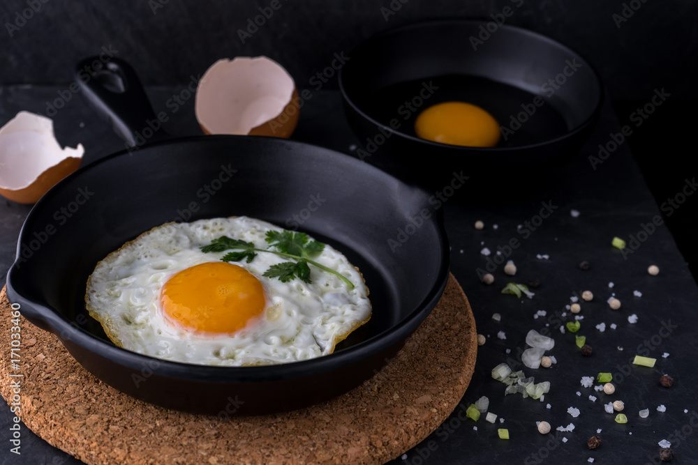 fried egg in black pan and ingredient on dark background fried egg in black pan and ingredient on dark background