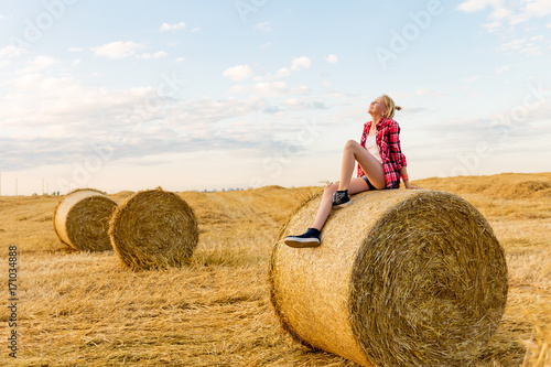 Young girl on straw sheaves in a field