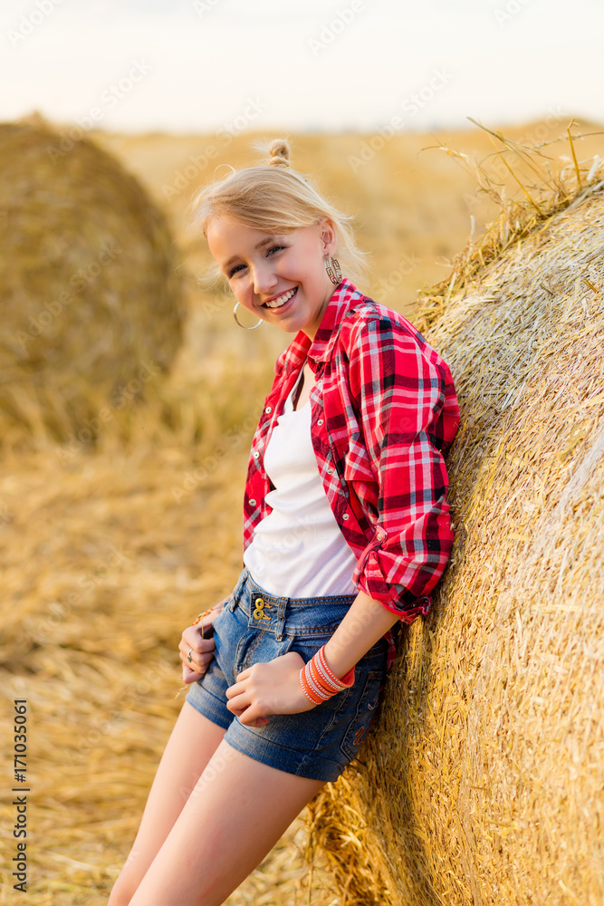 Young girl on straw sheaves in a field Young girl on straw sheaves in a field