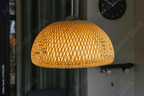 bamboo pendant light lamp hanging above white walls and wall clock