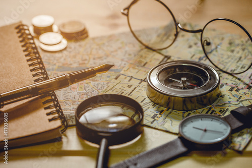 The compass is placed on a city map with objects nearby. Tone of photo is vintage style.