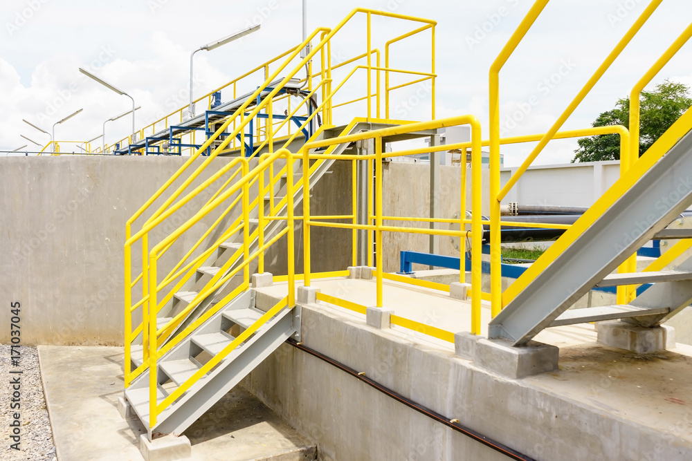 Yellow steel staircase with a walk up to the top of wastewater treatment plant