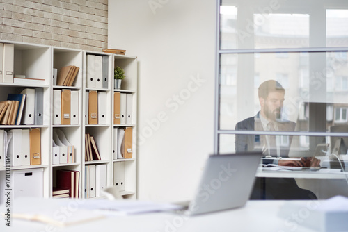 Background image of modern office space with blurred businessman working behind glass wall, copy space © Seventyfour