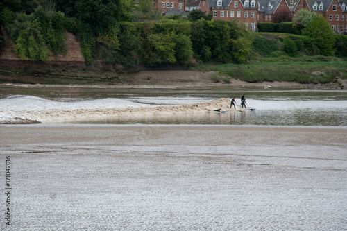 Surfers ride the Severn Bore tidal wave at Newnham-on-Severn, Gloucestershire photo