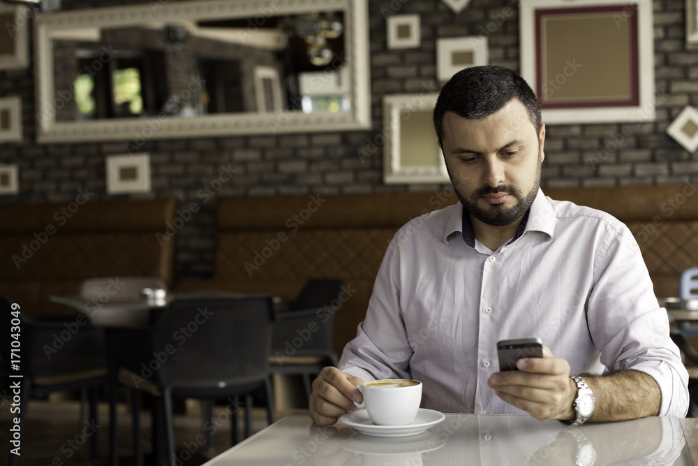 Handsome man texting on the phone in cafe Handsome man texting on the phone in cafe