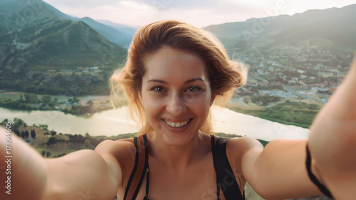 Beautiful young woman doing selfie in the mountains