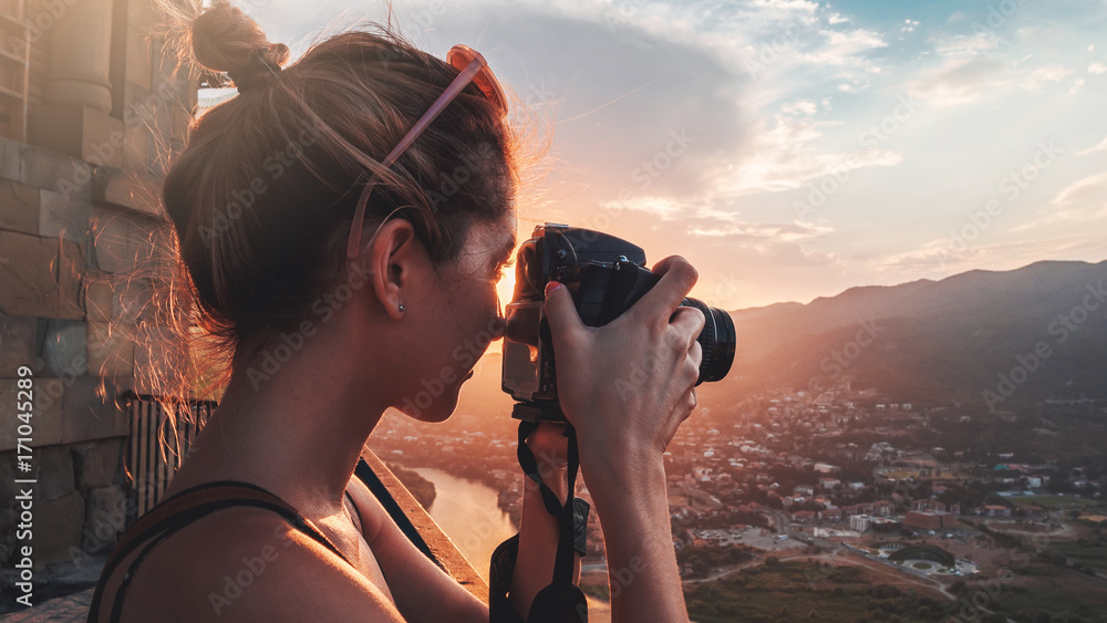 Female photographer, taking pictures of mountain landscape at sunset