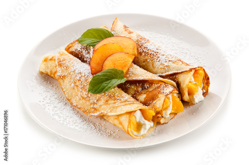 Crepes with peaches and cream on white background 