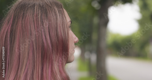 happy teen girl with purple hair standing in town side view