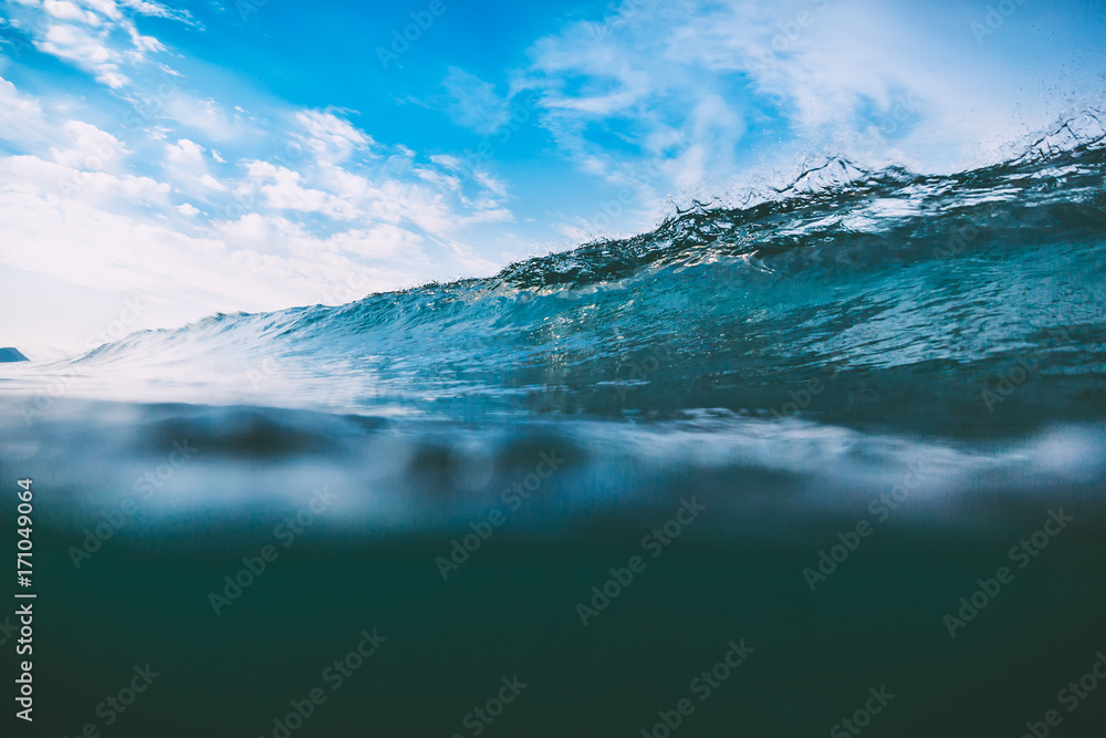 Crashing blue wave in ocean. Crystal wave and sun