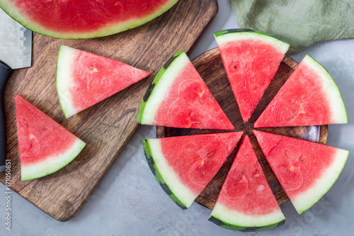 Slices of fresh seedless watermelon cut into triangle shape laying on wooden plate, flat lay, horizontal