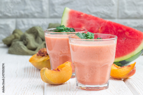 Watermelon, peach, mint and coconut milk smoothie in glass on white wooden background, horizontal, copy space