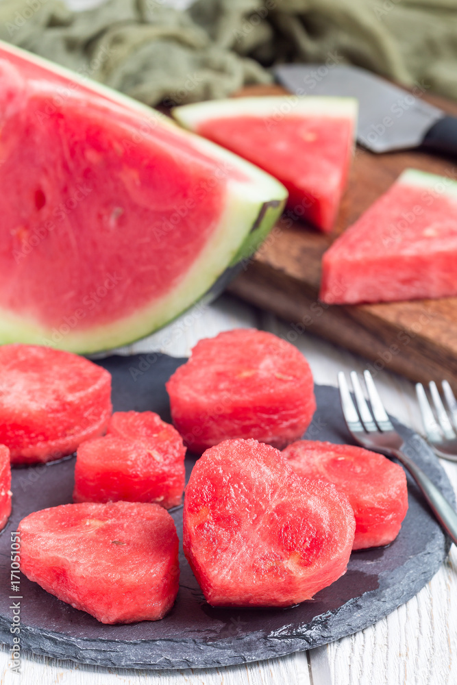 Slices of fresh seedless watermelon cut into heart shape on slate board, vertical Slices of fresh seedless watermelon cut into heart shape on slate board, vertical