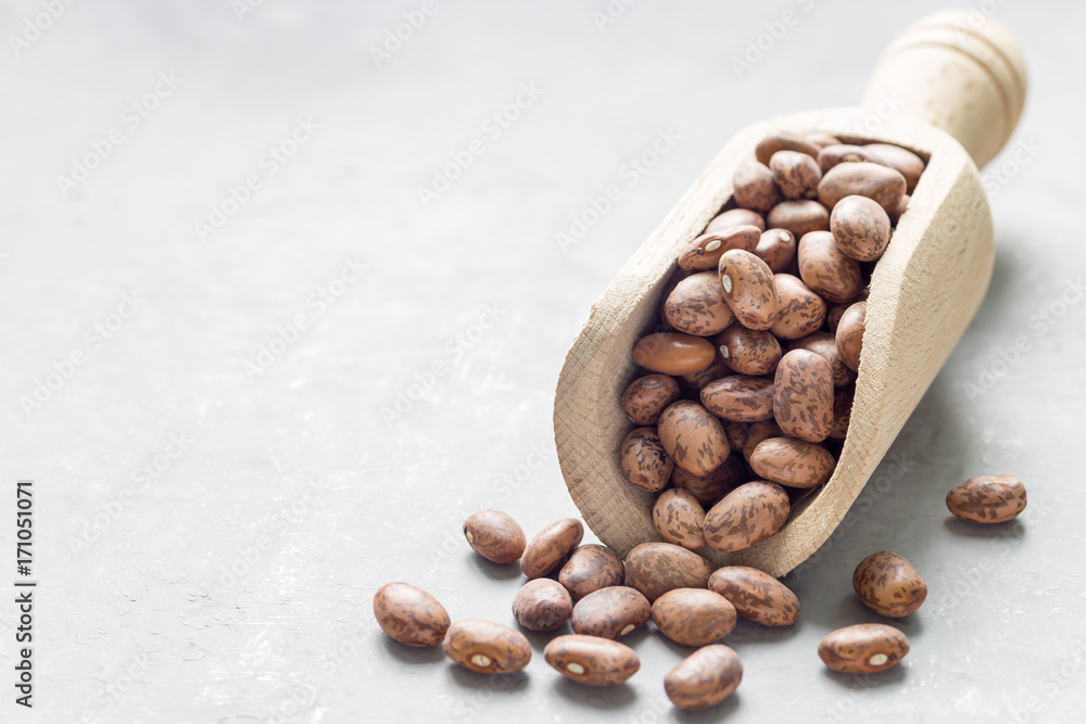 Uncooked dry pinto beans in a wooden scoop, copy space, horizontal Uncooked dry pinto beans in a wooden scoop, copy space, horizontal