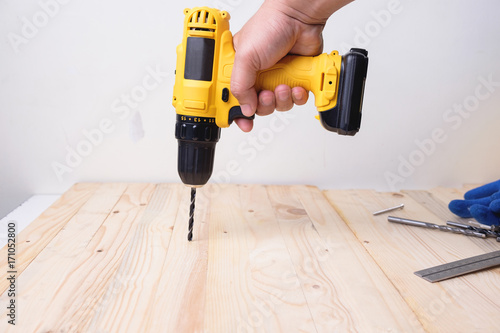 Craftsman working with power drill on wooden plank