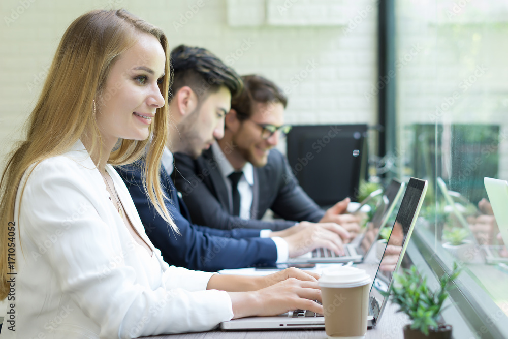 Obraz premium Businesswoman using laptop to work while coworker interacting in the background in the office