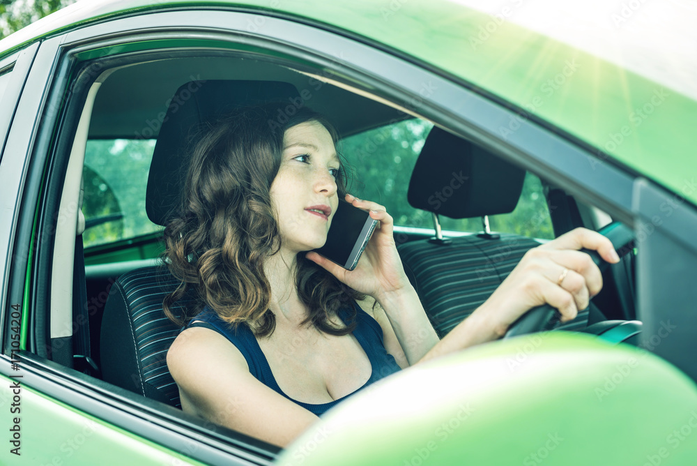 Woman driver talking on a phone in the car. Distracted and dangerous driving. The traffic violation. Woman driver talking on a phone in the car. Distracted and dangerous driving. The traffic violation.