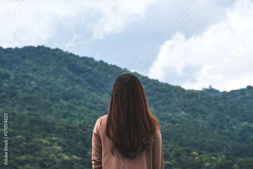 A woman turn back and standing with blue sky , green nature and mountain background