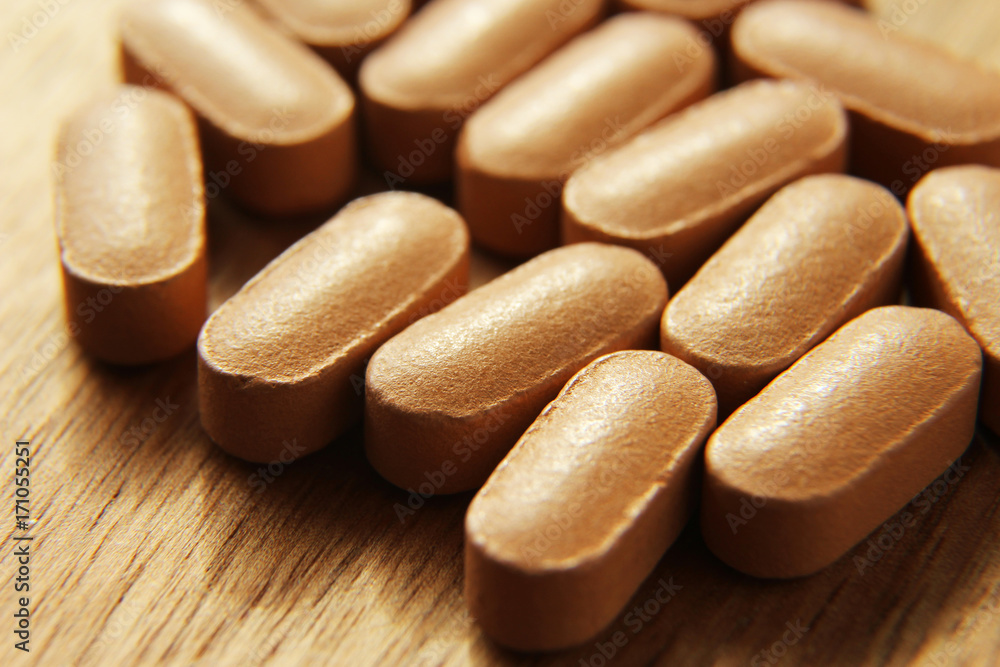 Medical pills on a wooden table.This image is a close up macro shot and has selective focusing. Medical pills on a wooden table.This image is a close up macro shot and has selective focusing.