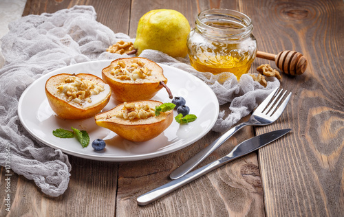 Pears baked with Ricotta cheese, nuts, honey and cinnamon on rustic wooden background photo