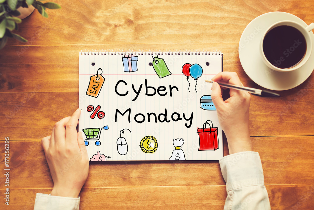 Cyber Monday text with a person holding a pen on a wooden desk Cyber Monday text with a person holding a pen on a wooden desk