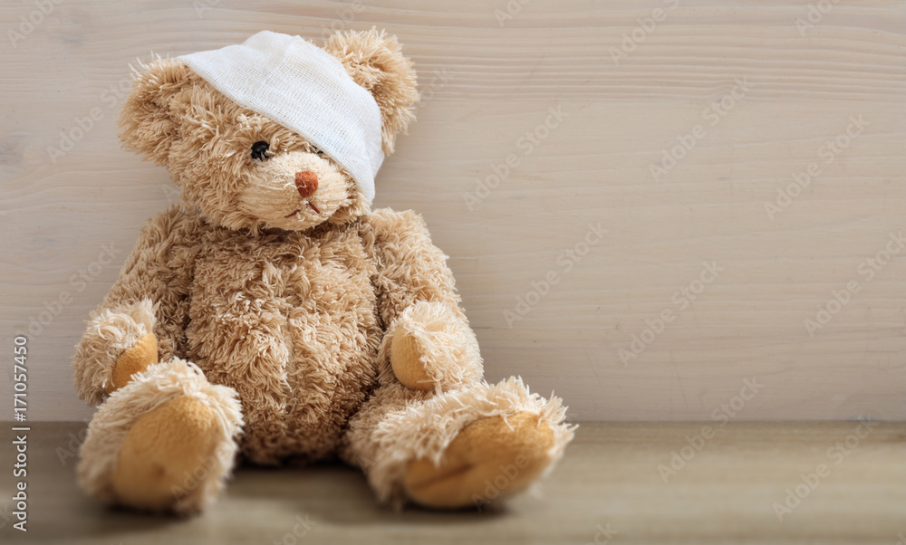 Teddy bear with bandage on a wooden floor Teddy bear with bandage on a wooden floor
